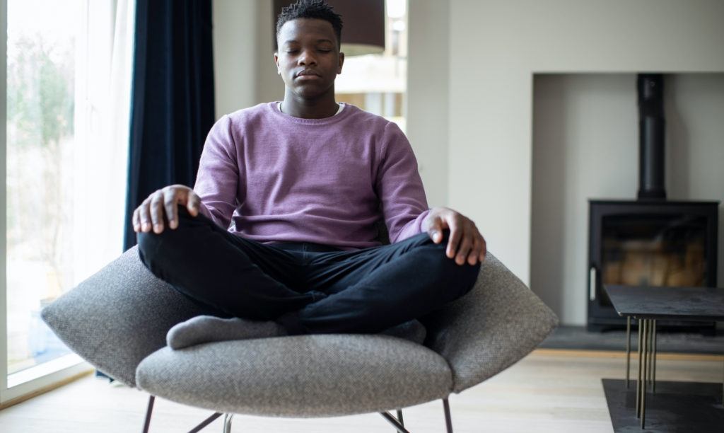 Young man meditating seated in chair